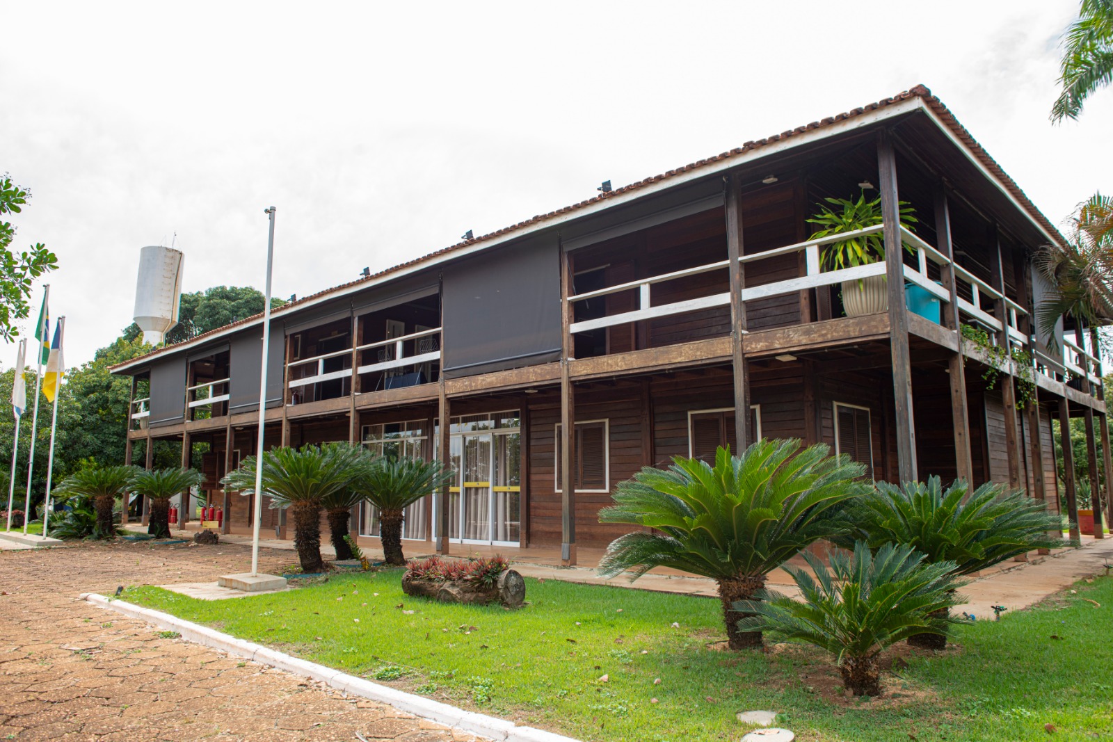 Imagem de uma construção com dois andares e árvores na entrada